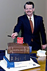 Professor Richard Gruner prepares to slice a specially designed cake that looks like intellectual property books. The cake was served to John Marshall staff at a good-bye party for Gruner on 3-East.